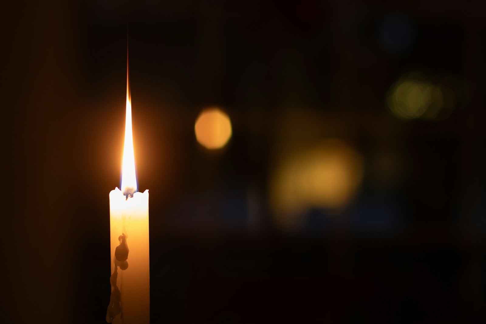 A single lit candle glowing in the dark